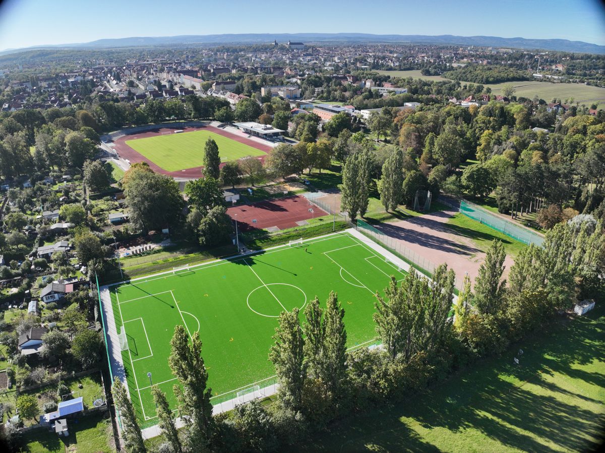 Luftaufnahme einer Sportanlage mit Rasengroßspielfeld, Laufbahn und Nebenflächen