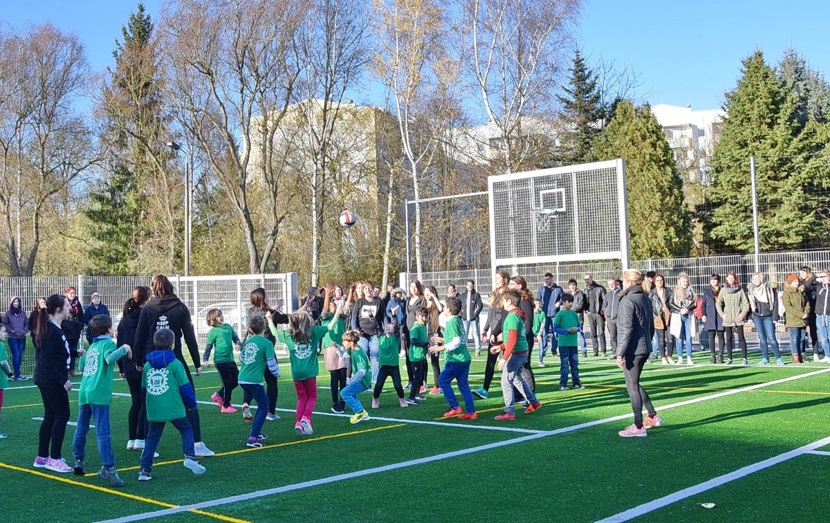 Einweihung einer Sportanlage: viele Kinder in grünen Trikots auf dem Kunstrasen